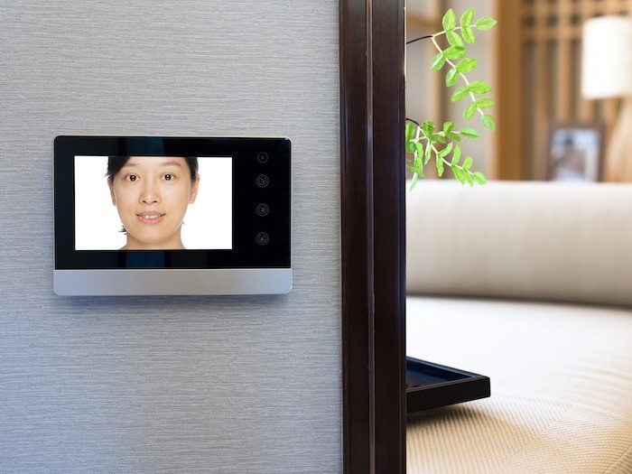 A room with wall-mounted video doorbell screen.